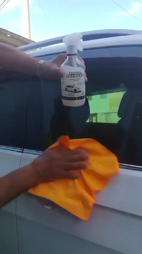 Frasco borrifador da Resina Extreme e toalha de microfibra na porta de um carro branco