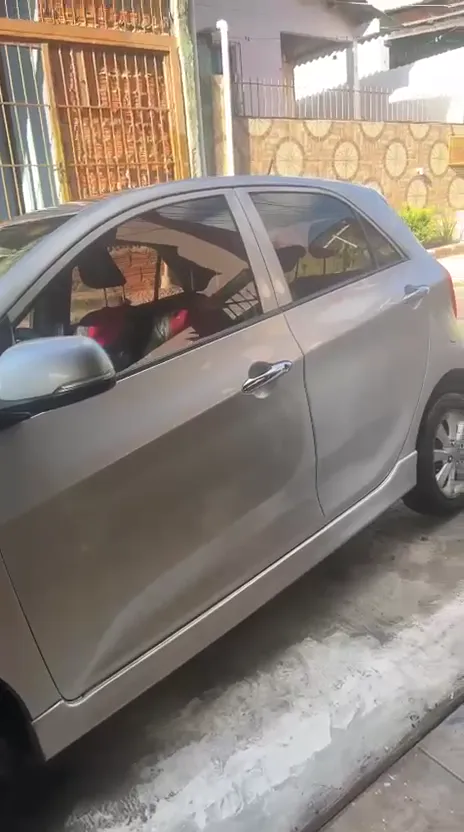 Carro prata compacto estacionado em frente a uma casa